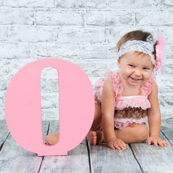 Beautiful and cute girl in a pink dress with the letter O. Emotional girl. — Stock Photo, Image