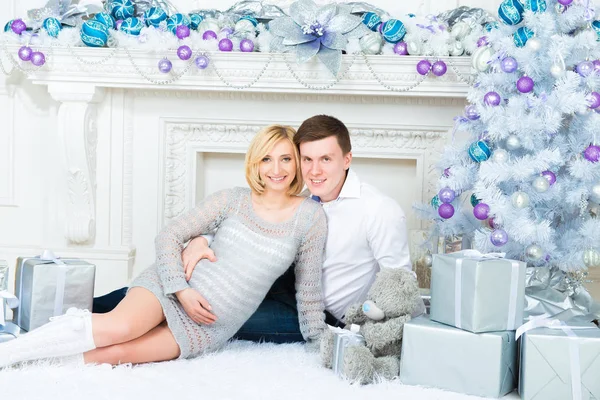 若いカップルが妊娠とクリスマス、クリスマス ツリーの背景で待機しています。 — ストック写真