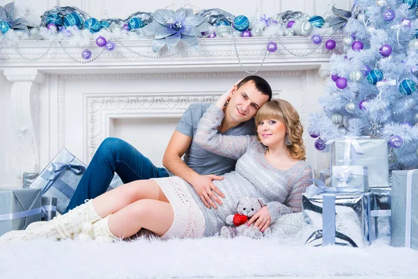 Embarazo y Navidad, pareja joven están esperando en el fondo de un árbol de Navidad —  Fotos de Stock