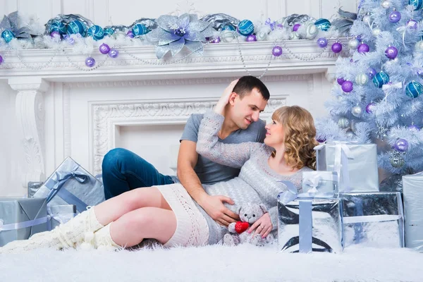 Gebelik ve Noel, Noel ağacı arka plan üzerinde genç çift bekliyor — Stok fotoğraf