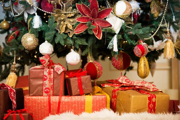 Luminoso studio di foto di scatole regalo di fronte a uno splendido albero di Natale lussureggiante, decorato in rosso e oro . — Foto Stock