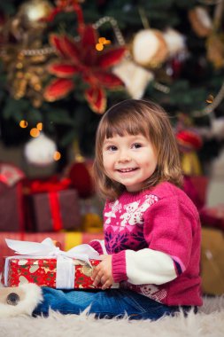 Yeni yıl ağacı bir arka plan üzerinde elinde bir hediye ile mutlu kız.