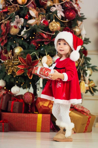 Gelukkig meisje met een geschenk in handen op een achtergrond van een nieuwe jaar boom. — Stockfoto