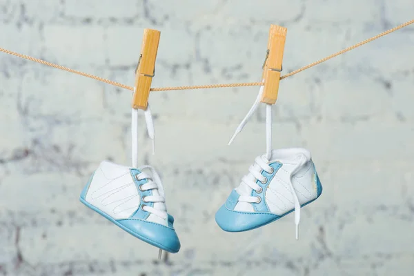 Babyblaue Schuhe an einem Seil gegen eine weiße Ziegelwand. — Stockfoto