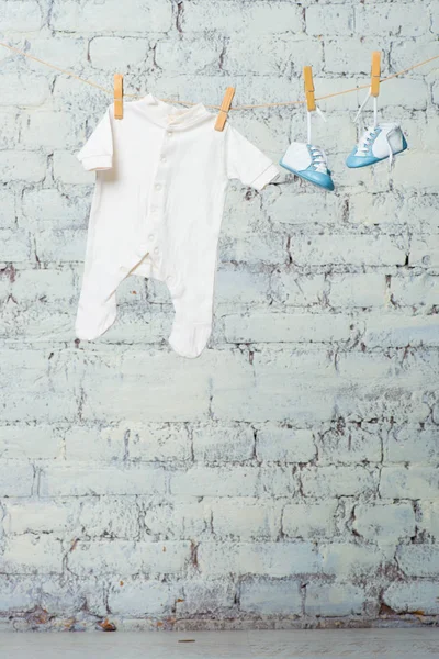 Детское белое тело и синие туфли на веревке против белой кирпичной стены . — стоковое фото