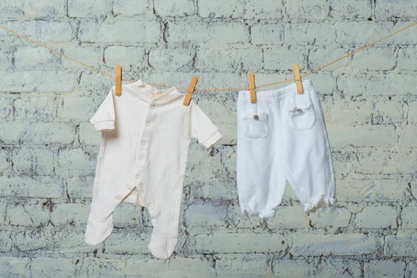 Cuerpo blanco de los niños y pantimedias secas en una cuerda contra una pared de ladrillo blanco . — Foto de Stock