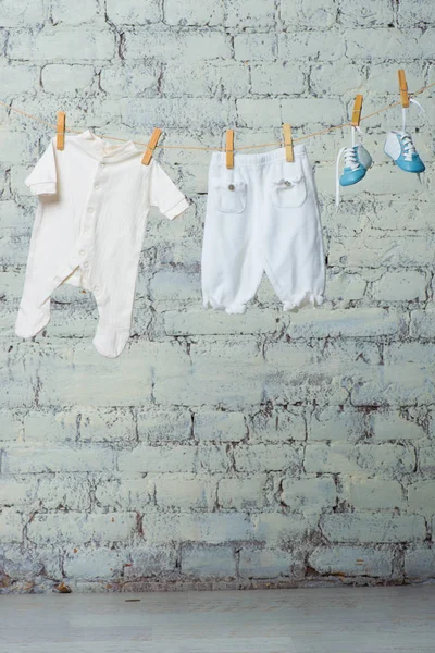 Corpo branco de crianças, botas e meia-calça seca em uma corda contra uma parede de tijolo branco . — Fotografia de Stock