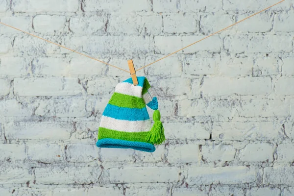 Casquette bébé et baskets vont sécher sur une corde sur un mur de briques blanches . — Photo