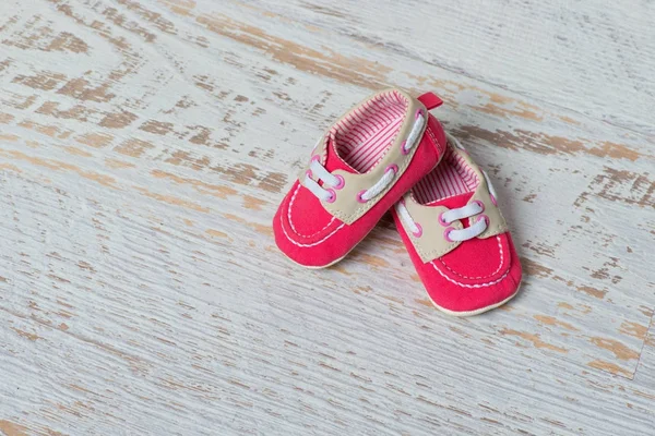 Bebé zapatos rojos en una cuerda contra una pared de ladrillo blanco . — Foto de Stock