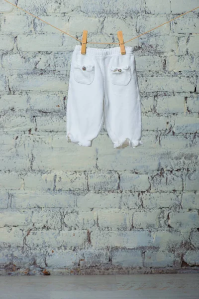 Bebé pantimedias secas en una cuerda contra una pared de ladrillo blanco . — Foto de Stock