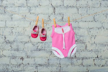 Pembe çocuk vücut, önlük ve kırmızı ayakkabılar, Kuru Beyaz duvara karşı bir ip üzerinde.