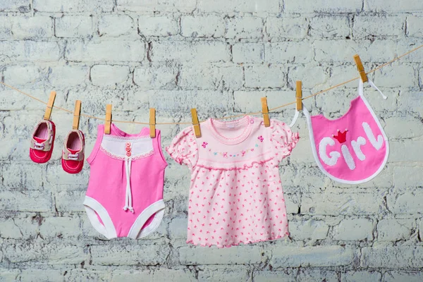 Dětské růžové bodik, bryndáček, šaty a červené boty pro holčičku, suché na laně zeď, bílá. — Stock fotografie
