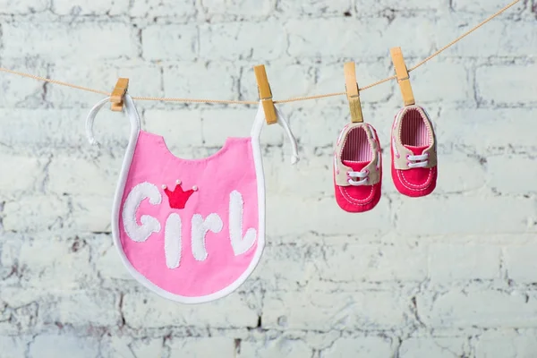 Niños niño saliva rosa y zapatos rojos en una cuerda contra una pared de ladrillo blanco . — Foto de Stock