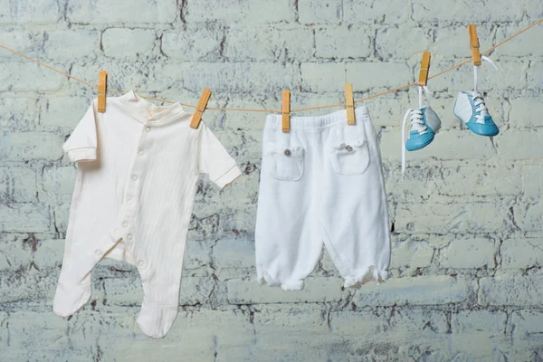 Childrens wit lichaam, laarzen en panty drogen op een touw tegen een witte muur. — Stockfoto