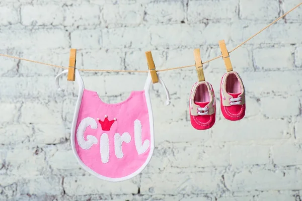 Niños niño saliva rosa y zapatos rojos en una cuerda contra una pared de ladrillo blanco . — Foto de Stock