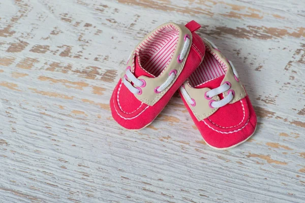 Baby red shoes on a rope against a white brick wall. — Stock Photo, Image