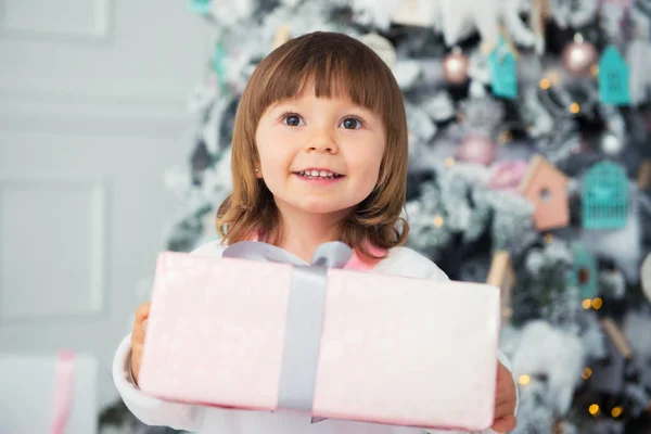 Regalo de Año Nuevo, emociones de felicidad y alegría. La niña sonriente da un regalo. Primer plano. En el interior . —  Fotos de Stock