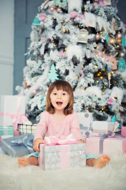 Noel hediye Noel ağacı yakınındaki ile oturan olumlu neşeli bebek kız. Yeni Yılınız Kutlu Olsun