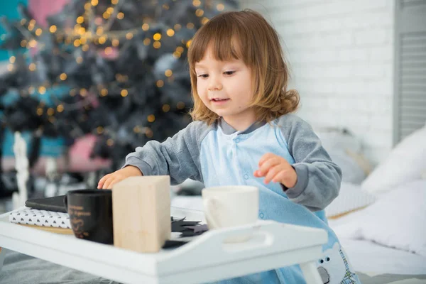 Pijama ile Noel hediyeleri yeni yıl ağacı yakınındaki oturan ve kartopu oynarken duygusal gülümseyen küçük kız — Stok fotoğraf