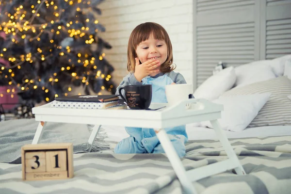 Nochevieja, 31 de diciembre. Linda niña en pijama con taza cerca del árbol de Navidad —  Fotos de Stock