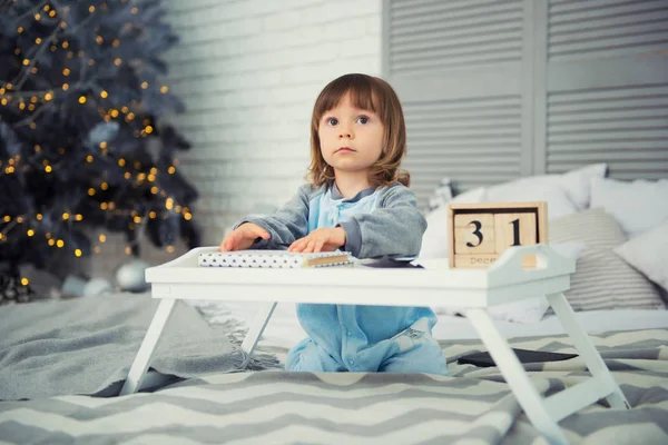 Συναισθηματική χαμογελαστό κοριτσάκι κάθεται σε pajama με τα δώρα Χριστουγέννων κοντά νέο ετών δέντρο και παίζοντας χιονόμπαλες — Φωτογραφία Αρχείου
