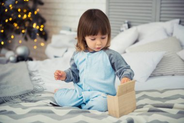 Pijama ile Noel hediyeleri yeni yıl ağacı yakınındaki oturan ve kartopu oynarken duygusal gülümseyen küçük kız
