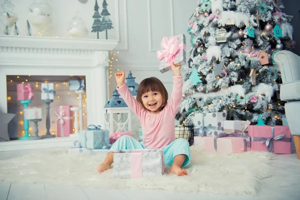 Bébé fille gaie positive assis avec cadeau de Noël près de l'arbre de Noël. Bonne année — Photo