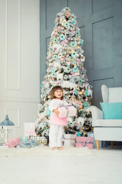 Childrens delight. Little two-year-old girl is happy near the Christmas tree. New Year is soon. — Stock Photo, Image