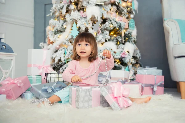 Little baby girl opens New Year gift near Christmas tree — Stock Photo, Image