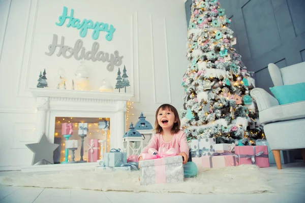 Little baby girl opens New Year gift near Christmas tree — Stock Photo, Image