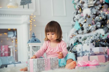 Noel hediye Noel ağacı yakınındaki ile oturan olumlu neşeli bebek kız. Yeni Yılınız Kutlu Olsun