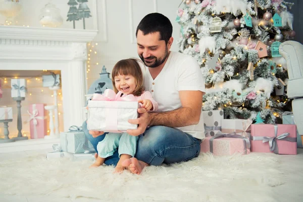 Батько і дочка сидять і відкриття Різдвяний подарунок біля новорічної ялинки. З новим роком — стокове фото