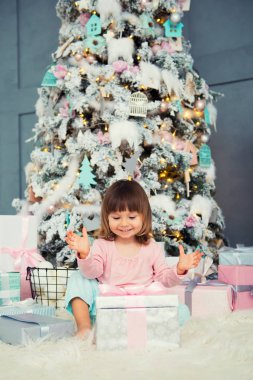 Noel hediye Noel ağacı yakınındaki ile oturan olumlu neşeli bebek kız. Yeni Yılınız Kutlu Olsun