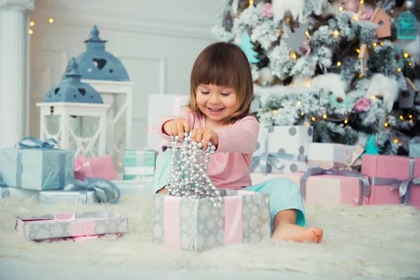 Pozytywne Wesoła dziewczynka siedzi z Boże Narodzenie prezent w pobliżu choinki. Szczęśliwego nowego roku — Zdjęcie stockowe