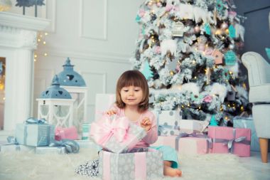 Noel hediye Noel ağacı yakınındaki ile oturan olumlu neşeli bebek kız. Yeni Yılınız Kutlu Olsun