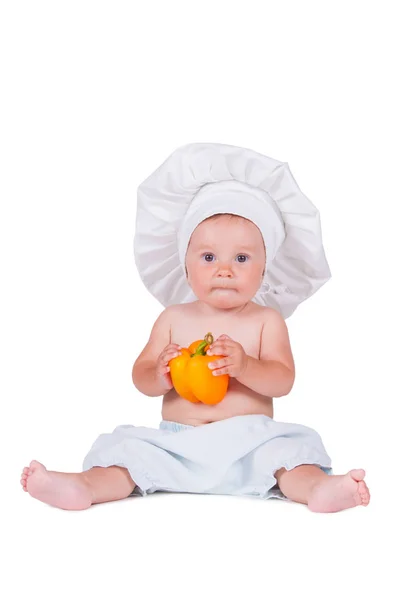 Menina engraçada na roupa de um cozinheiro com pimenta em suas mãos . — Fotografia de Stock