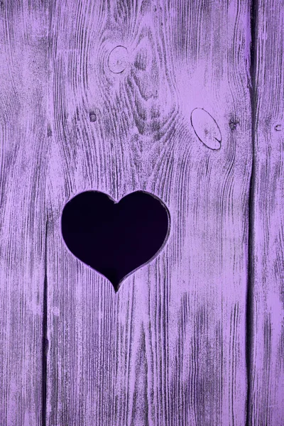 Corazón tallado en una tabla de madera púrpura. Contexto . — Foto de Stock