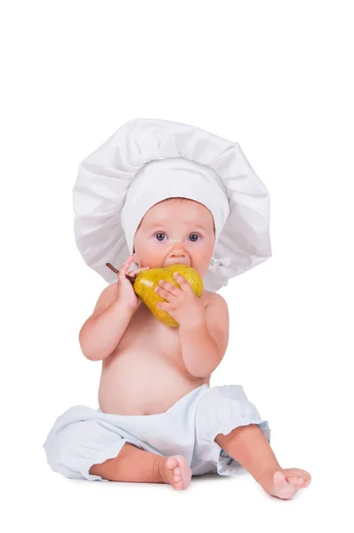 Criança alegre com uma pêra nas mãos em um terno de chef em um fundo branco . — Fotografia de Stock