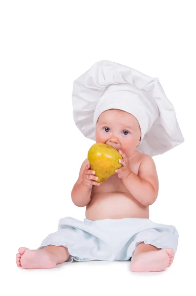 Glada lilla barnet med ett päron i hans händer i en kock kostym på vit bakgrund. — Stockfoto