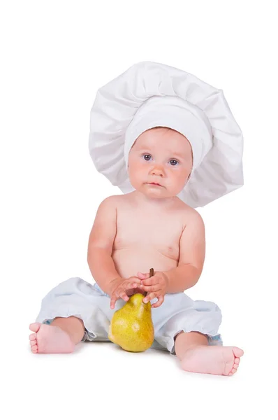 Glada lilla barnet med ett päron i hans händer i en kock kostym på vit bakgrund. — Stockfoto