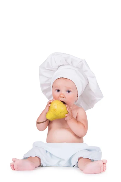 Niño alegre con una pera en las manos en un traje de chef sobre un fondo blanco . —  Fotos de Stock