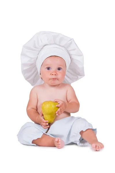 Petit enfant joyeux avec une poire à la main dans un costume de chef sur fond blanc . — Photo