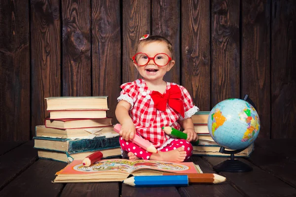 Happy miły dziewczynka z okulary i kredki na tle książek i świata — Zdjęcie stockowe
