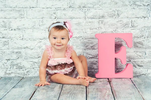 Beautiful and cute girl in pink dress with the letter E. Emotional girl. — Stock Photo, Image
