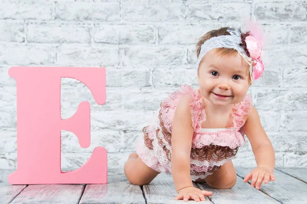 Vacker och söt flicka i rosa klänning med bokstaven E. känslomässiga flicka. — Stockfoto