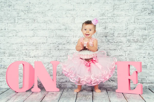 Vacker och söt tjej i en rosa klänning med bokstäverna en på hennes första födelsedag. Känslomässiga flicka. — Stockfoto