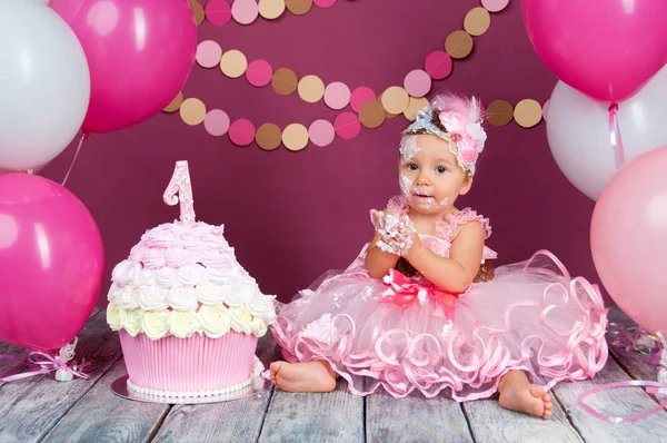 Küçük kızın doğum günü kızı bir kek içine sürülür. İlk pasta. İlk pasta kullanımı. Şut kek. — Stok fotoğraf