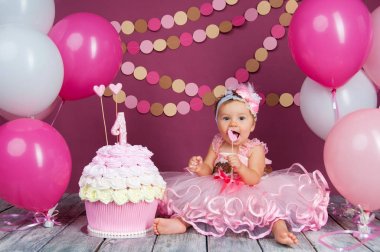 Küçük kızın doğum günü kızı bir kek içine sürülür. İlk pasta. İlk pasta kullanımı. Şut kek.