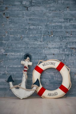 Bir deniz konulu bir kompozisyon bir çapa ve yaşam yüzüğü gri tuğla duvar ile.