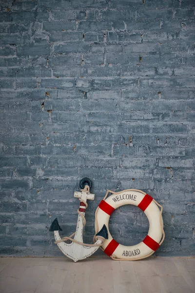 A composition on a sea theme with an anchor and life ring on a gray brick wall. — Stock Photo, Image